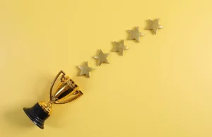 A small gold trophy and a row of five gold stars on a yellow background