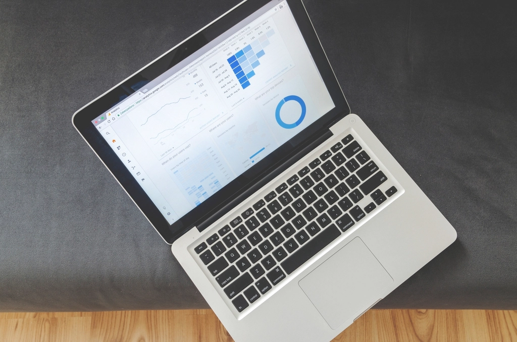 An open laptop showing charts and a donut graph on a dark surface